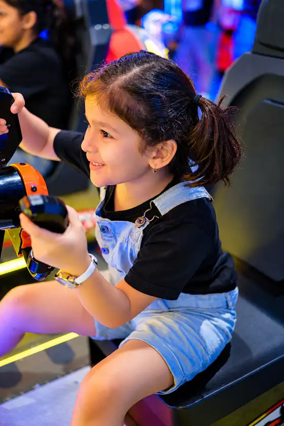 A child smiling while playing an arcade racing game
