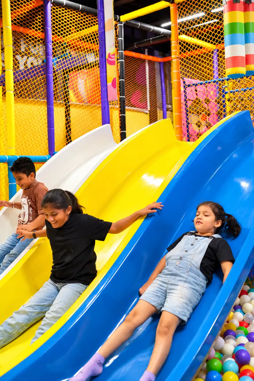 Children sliding down a bright blue and yellow slide