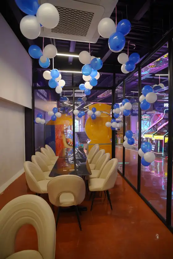 The private party room decorated with blue and white balloons, next to the arcade floor