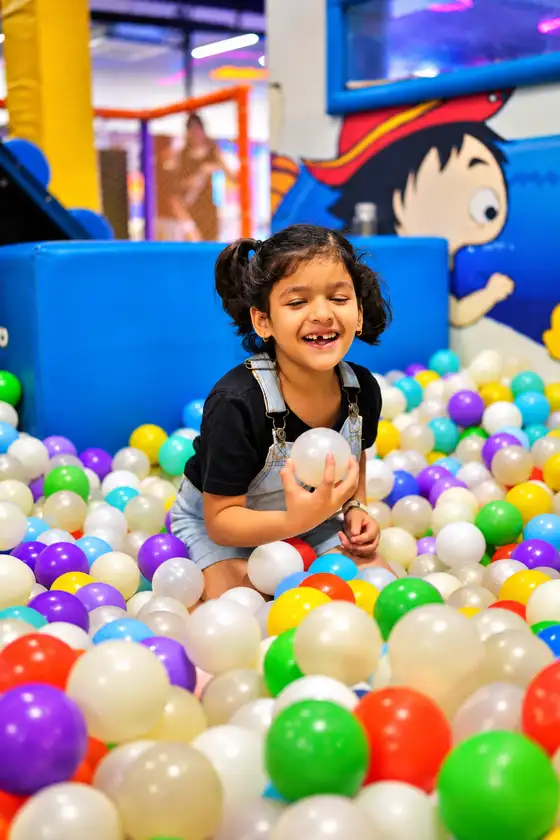 A child laughing in a colourful ball pit